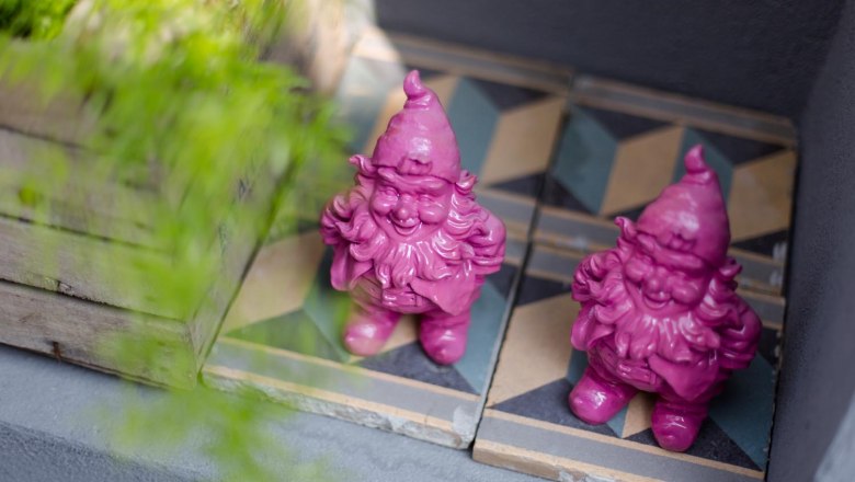 Klinger's guest house, © Astrid Bartl Two pink garden gnomes on patterned tiles next to a wooden box with plants.