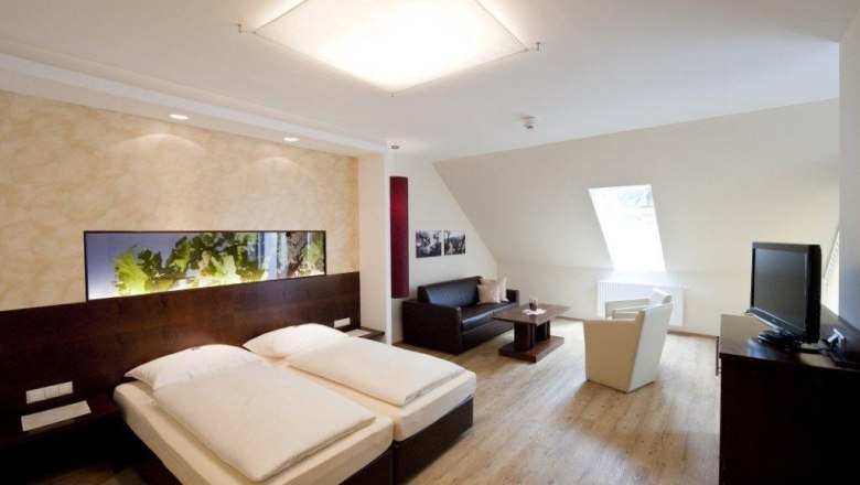 Room example, © Prankl Modernly furnished hotel room with double bed, sofa, armchair and TV.