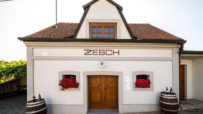 Wine cellar, © Fam. Zesch Small building with the inscription 'Zesch', two wine barrels and red flowers.
