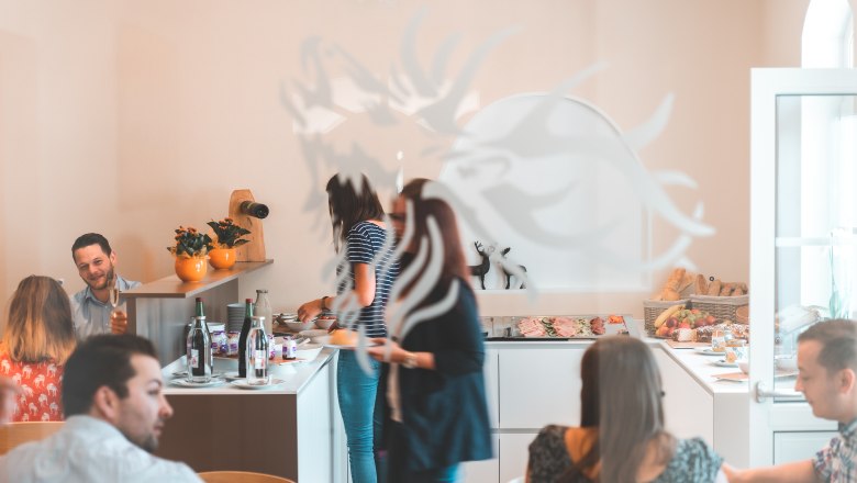 Breakfast buffet, © Matthias Auer People help themselves to a breakfast buffet in a bright room.