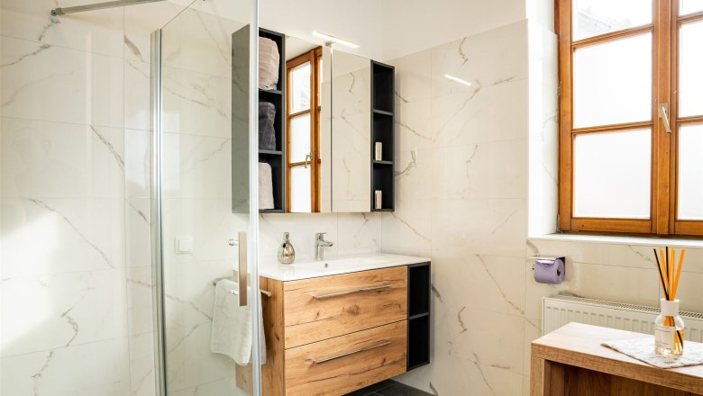 Bathroom, © Georg Pomassl Modern bathroom with wooden furniture, large window front and glass shower.