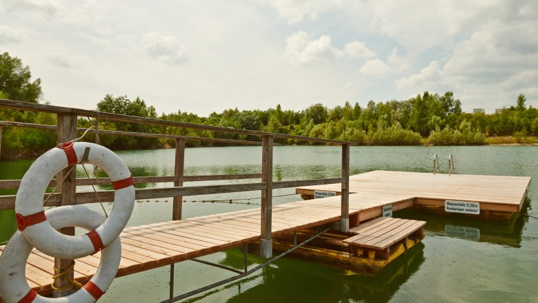 Swimming pond Persenbeug - Gottsdorf, © Klaus Engelmayer A wooden jetty with lifebuoys on a quiet lake surrounded by trees.