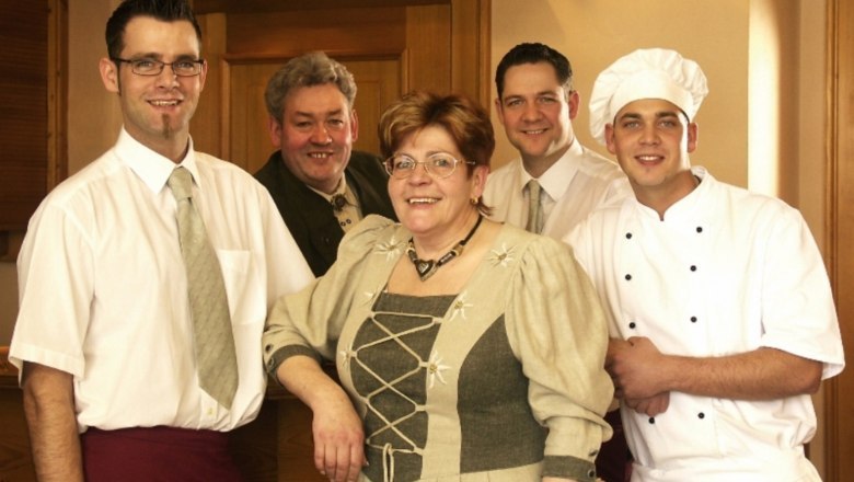 Schweinberger family, © Fam. Schweinberger Five people in traditional clothing and chef's uniforms pose smiling in a room.