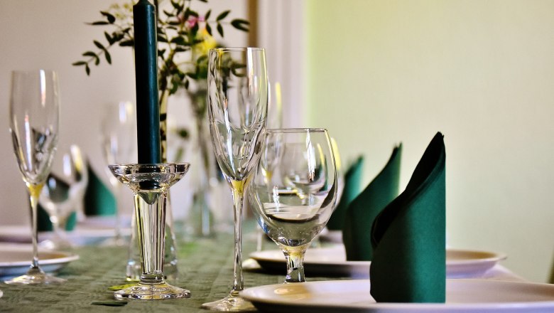 Dine in comfort, © gemeinfrei Elegant table with wine glasses, candle and folded napkins.