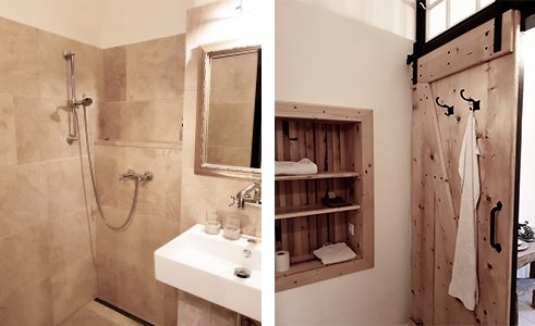 Bathroom, © Gröger A bathroom with a shower, a washbasin and a wooden shelf next to a sliding door.