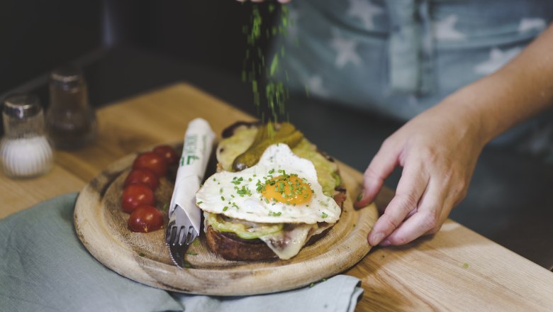 TDR dishes, © Buschenschank Buder A plate with a sandwich, fried egg and tomatoes, garnished with chives.