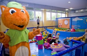 kids space Toddler area, © kids space gars Children play in an indoor play area with a large orange mascot.