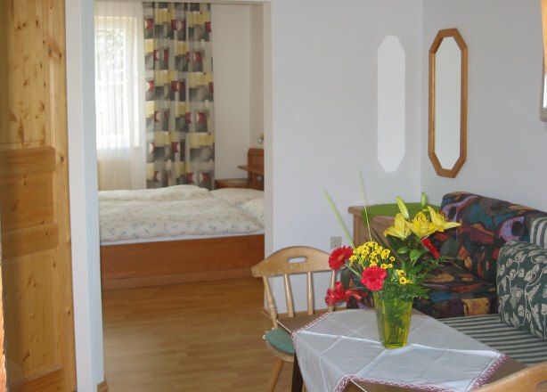 Ottensteinerhof-Waldblick, © Ottensteinerhof-Waldblick Living room with table, bouquet of flowers and view into the bedroom.