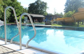 Weitersfeld adventure pool, © Marktgemeinde Weitersfeld An outdoor pool with slide and ladder, surrounded by trees and a building in the background.