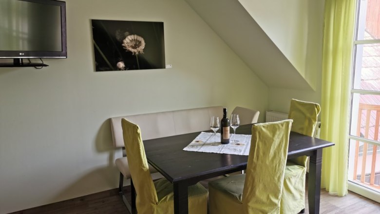 Grüne Veltliner" vacation apartment, © Weinhof Brauner Dining area in a vacation apartment with table, chairs and bottle of wine.
