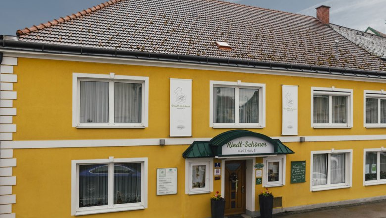 Inn with many organic products, © Niederösterreich Werbung/David Schreiber Yellow guest house with green awning and several windows.