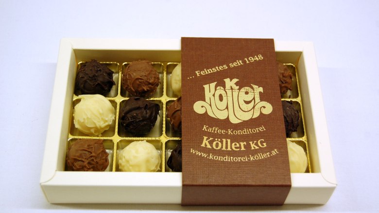 finest handmade chocolates, © Konditorei Köller A box of handmade chocolates from Köller KG, partially opened, on a white background.