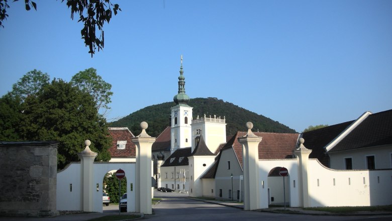 Heiligenkreuz, © Heiligenkreuz Entrance gate of Heiligenkreuz Abbey with church tower in the background.