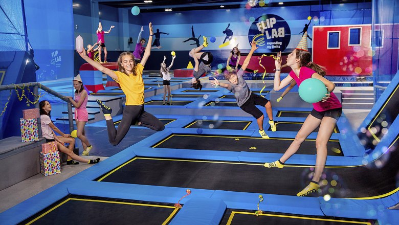 Flip Lab, © FLIP LAB GmbH & Co.KG/Nadine Studeny Photography People jumping on trampolines in a hall with the 'Flip Lab' logo.