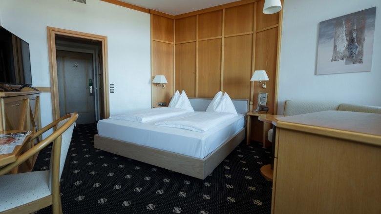 Double room, © Sporthotel Semmering A hotel room with a double bed, wooden furniture and a TV.