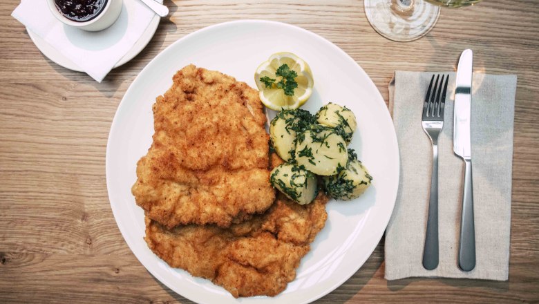 Inn cuisine with creative accents, © Astrid Bartl Wiener schnitzel with parsley potatoes and cranberries.