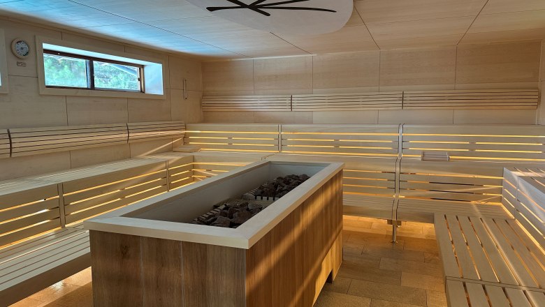 Zen sauna Linsberg Asia, © Linbsberg Asia Interior view of a modern sauna with wooden benches and a stove in the middle.