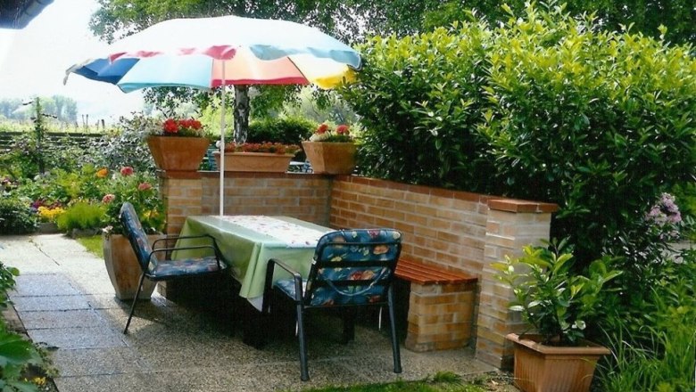 Garden seating area, © Ivan Sigl Garden with table, chairs and parasol.