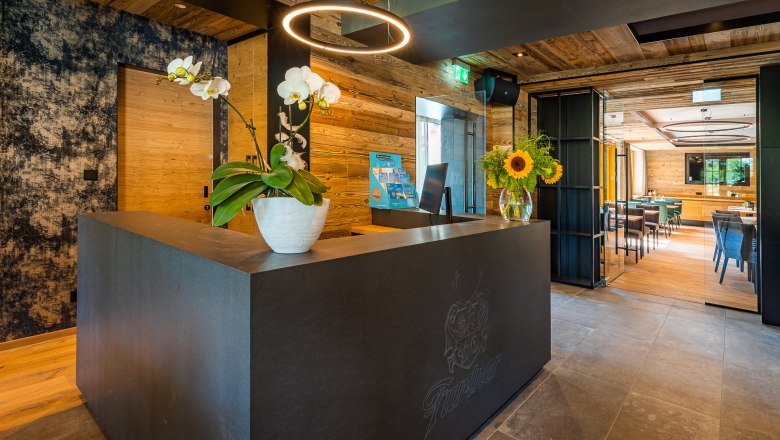 Reception, © Christian Kremsl Modern reception with wood paneling, orchids and sunflowers on the counter.