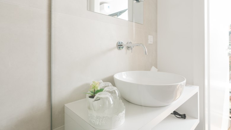 Ipsmiller Apartments, © Michael Reidinger Modern bathroom with round washbasin and mirror.