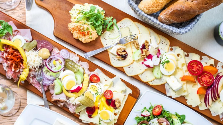 Heurigen snack at the Stadler winery, © Robert Herbst Various cold cuts and cheese platters with bread and salad on a table.