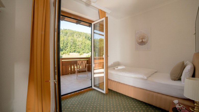 Single room with balcony 20, © Dorfschmiede eG Single room with balcony, single bed, open balcony door, view of green landscape.
