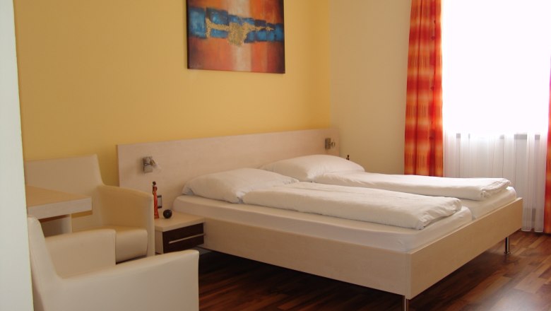 Kirchenwirt Jöch, © Kirchenwirt Jöch A modern hotel room with a double bed, yellow walls and an abstract painting.