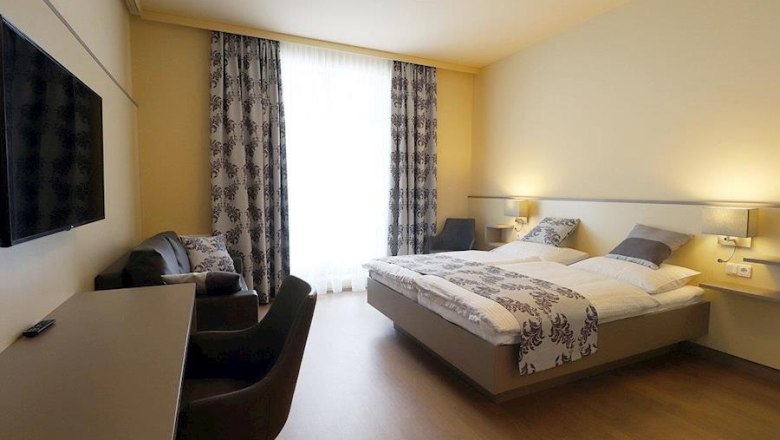 Kirchenwirt - Hotel - DZ Sonnwendstein, © Karin Stranz Modernly furnished hotel room with double bed, desk, TV and armchairs.