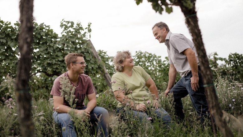 Palatinate winegrowing family, © Astrid Bartl Three people in a vineyard laughing together.