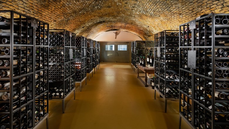Old wine archive of the Domäne Wachau, © Domäne Wachau Wine cellar with vaulted ceiling and shelves full of wine bottles.