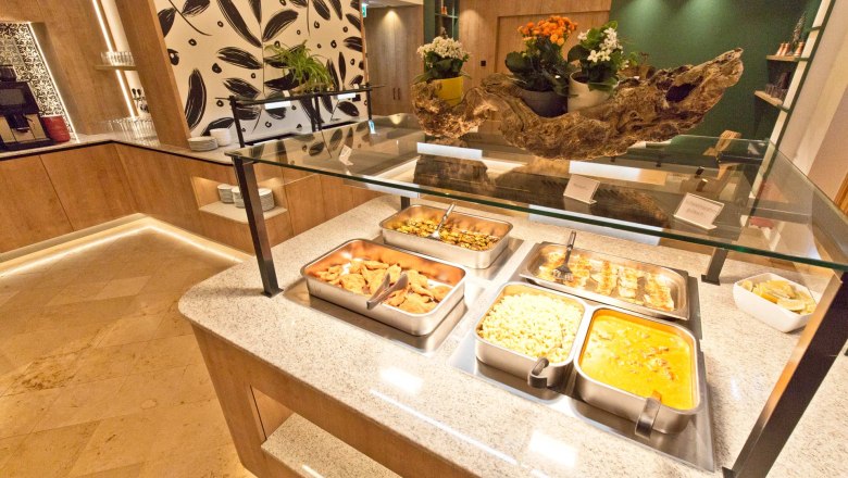 Flack Wirt - Buffet area, © Daniel Fischer Buffet area with various dishes in stainless steel containers, decorated with plants and wooden elements.