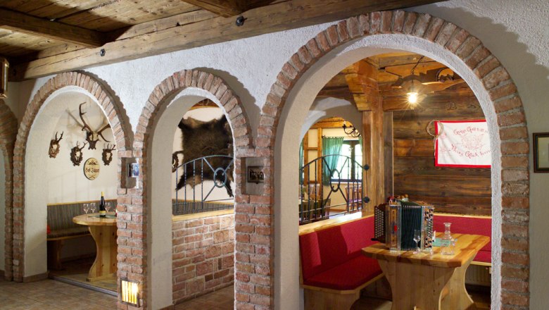 Restaurant, © Landstetter Landhaus Heuriger Rustic dining room with wooden furniture, brick arches and hunting trophies on the walls.