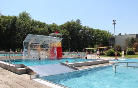 Neunkirchen Recreation Center, © Stadtgemeinde Neunkirchen Outdoor pool with climbing wall, surrounded by trees.