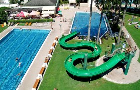 Thermal sports pool Mannersdorf am Leithagebirge, © Stadtgemeinde Mannersdorf/Leithagebirge Aerial view of an outdoor pool with two pools and a green water slide.