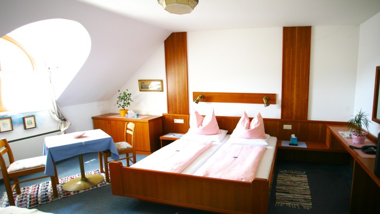 Inn-Pension "Drei Hacken", © Gasthof "Drei Hacken" Comfortable hotel room with double bed, wooden furniture and table with chairs.