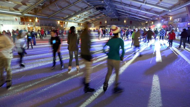 Amstetten ice rink, © Gerhard Sengstschmied People ice skating in an illuminated ice rink.