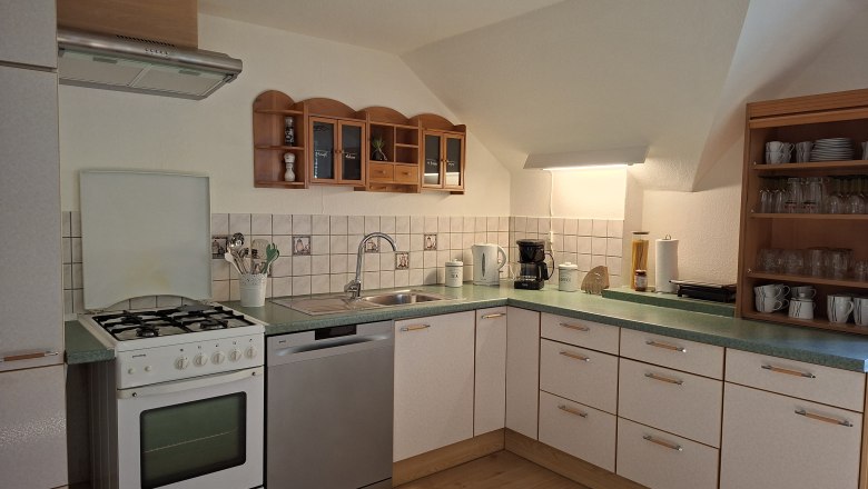 Kitchen, © Manuela Heher Corner kitchen with stove, sink, dishwasher and shelves.