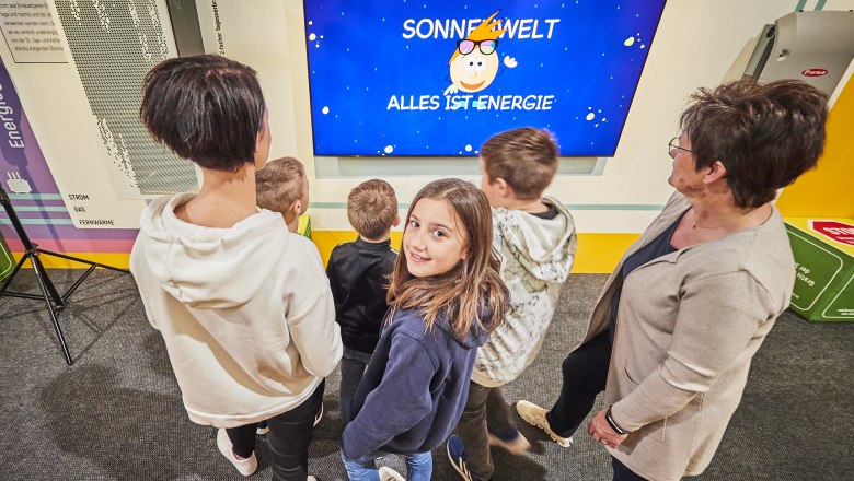 Special exhibition "The Powerchangers", © @ SONNENWELT/schewig Fotodesign Group of people looking at interactive exhibition about energy.