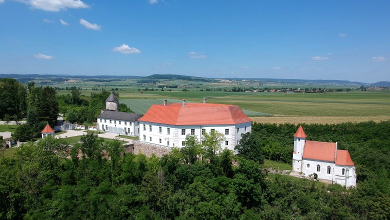 Viehofen Castle, © Sabine Figl, Schloss Viehofen Aerial view of Viehofen Castle with red roof, surrounded by green countryside and fields.