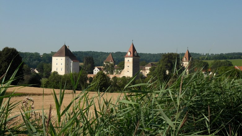 Großmugl, © Gemeinde Großmugl Castle with towers behind a field and tall grasses.