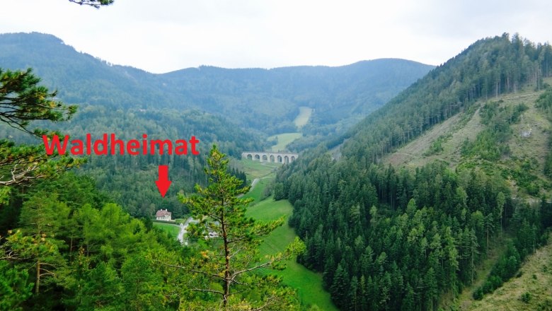 Location, © Philip Ospelt View of a wooded mountain landscape with a viaduct and a marked building called Waldheimat.