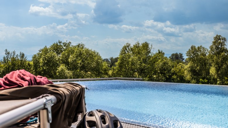 Pool, © Wiener Alpen / Martin Fülöp An infinity pool with trees in the background and a bicycle helmet in the foreground.