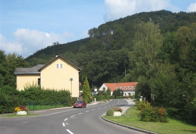Wolf trench, © Wolfsgraben Rural road with houses and wooded hill in the background.