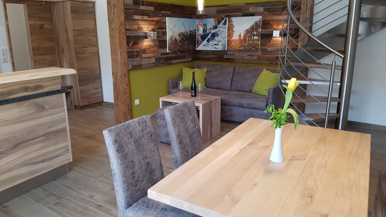 Apartment, © Winzerhaus Schöller Modern apartment with wooden furniture, gray sofa, yellow wall and spiral staircase.