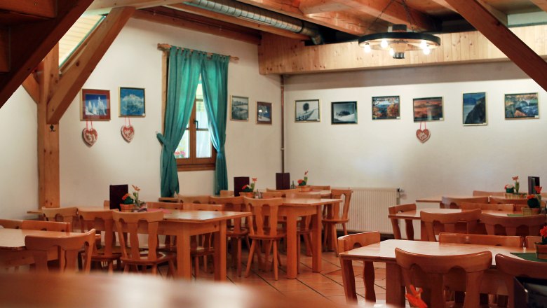 Tavern Moderbacher, © weinfranz.at Interior view of a rustic dining room with wooden furniture and pictures on the wall.
