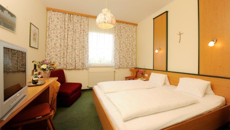 Room example, © Fam. Rethaller Comfortable hotel room with double bed, TV, flowers and curtains.