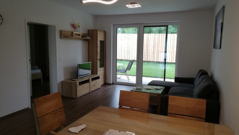 Living room, © Peter Hecht Modern living room with wooden furniture, gray sofa and large window overlooking the garden.