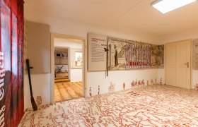 Fortified church documentation, © Wiener Alpen, Christian Kremsl Interior view of a museum room with historical maps and weapons on the walls, a large old map is drawn on the floor