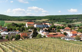 Enjoy and pause for thought in the Hundschupfen vineyard, © Weinstraße Weinviertel View of a village with vineyards in the foreground and hills in the background.