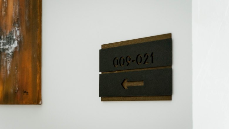 Hotel Lamede, © Hotel Lamede A sign with the inscription for room numbers '009-021' and an arrow pointing to the left on a white wall.